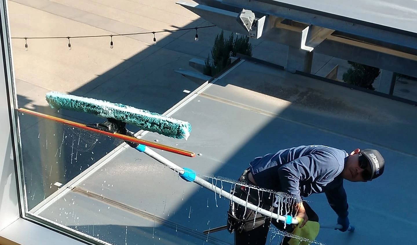 Fernando cleaning storefront glass with a water-fed pole