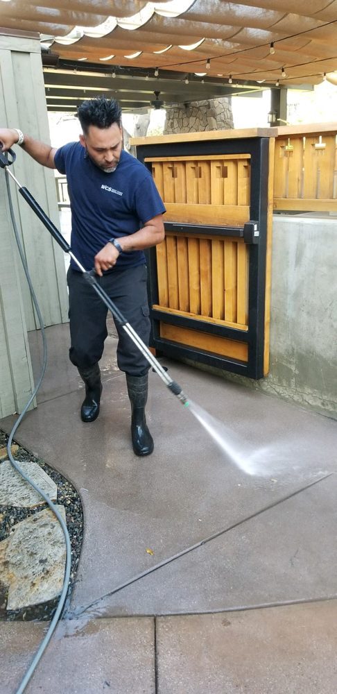 Technician pressure washing an entry walkway