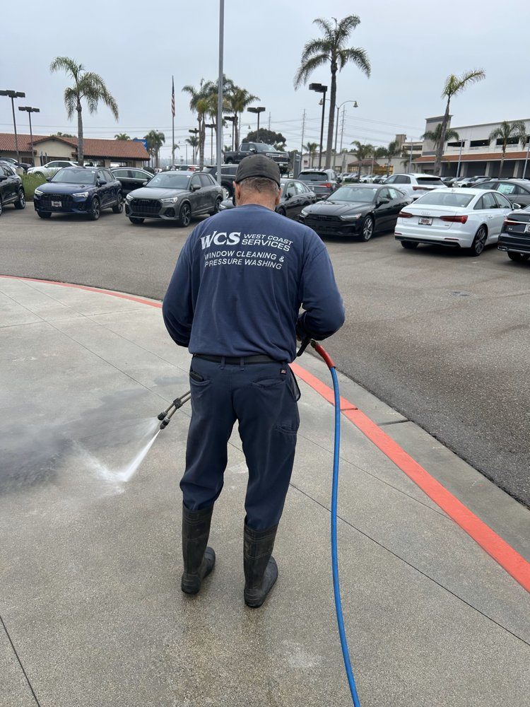 Technician pressure washing a dealership lot